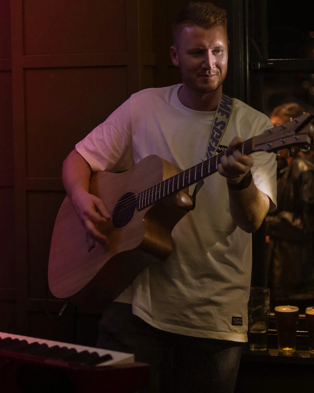 Red performing live in a tuxedo at a wedding, playing acoustic guitar